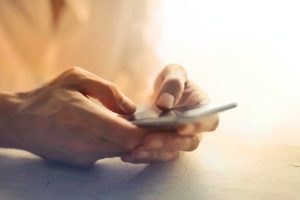 person holding white smartphone on white table